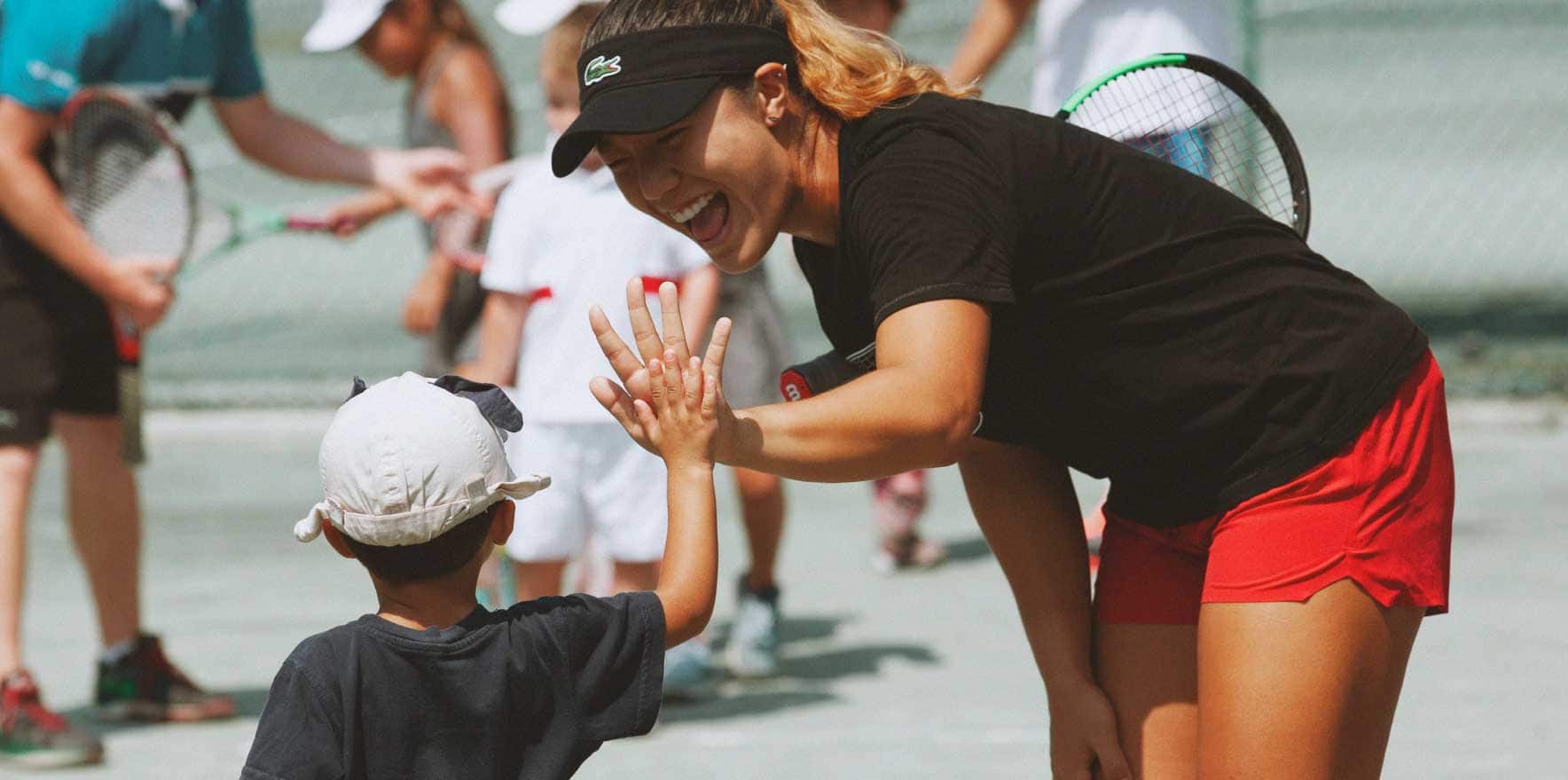 A women and a boy checking hands on a tennis court