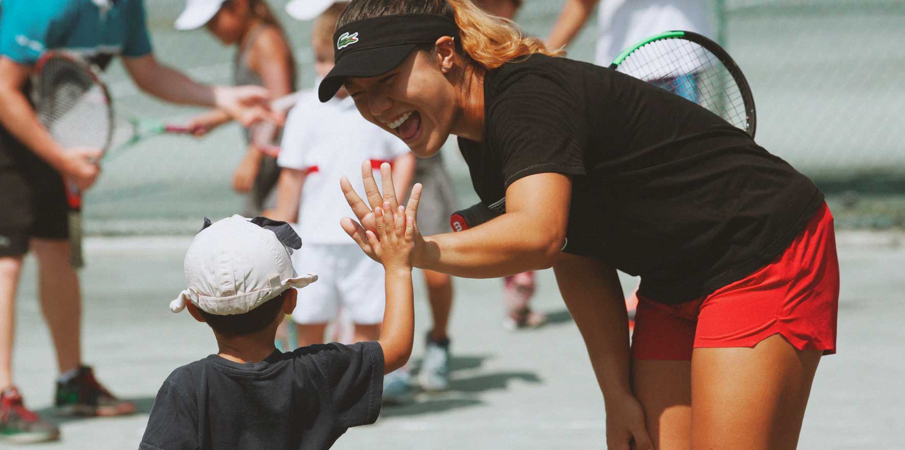 A women and a boy checking hands on a tennis court