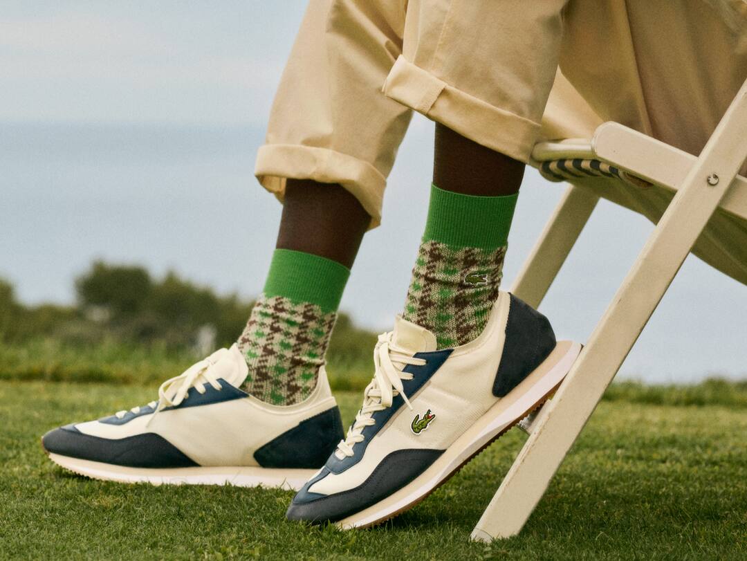 Sneakers Match Break de Lacoste port&eacute;es avec un chino beige et des chaussettes &agrave; carreaux.